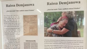 Foto: Ausstellungstafel mit Text und einem Foto zweier trauernder Menschen in der  Gedenkstätte Stalag © Stadt SHS