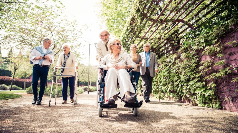 Ältere Menschen mit Rollator und Rollstuhl beim Spaziergang